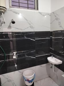 a black and white bathroom with a sink and a toilet at Shiv Shakti Homestay in Ujjain