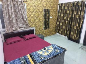 Schlafzimmer mit einem Bett mit roten Kissen und goldenen Tapeten in der Unterkunft Shiv Shakti Homestay in Ujjain