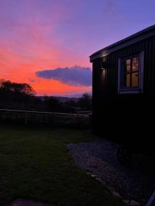 een huis met een zonsondergang op de achtergrond bij Modern Shepherd's Hut Retreat for 2, Dog Friendly in Llangoed