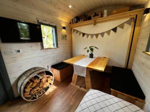 een kleine kamer met een tafel en een mand hout bij Modern Shepherd's Hut Retreat for 2, Dog Friendly in Llangoed