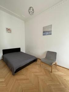 a bedroom with a bed and a chair in it at White Pearl Rooms in Budapest