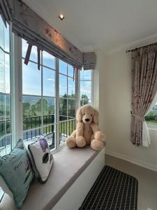 a stuffed teddy bear sitting on a window sill at Misty English Cottage in Ban Non Na Yao