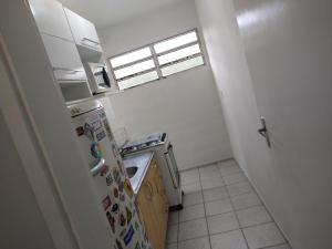 una pequeña cocina con nevera y ventana en Bate & Volta - Apartamentos com 2 quartos próximo ao SESC Bertioga, en Bertioga