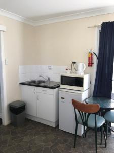 een kleine keuken met een wastafel en een tafel bij Australian Hotel Winton Cabins in Winton