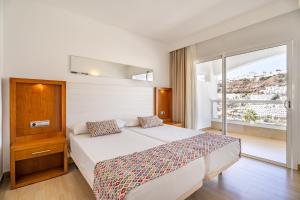 a bedroom with a bed and a large window at Apartamentos Altair in Puerto Rico de Gran Canaria