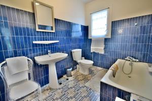 La salle de bains est pourvue de carrelage bleu, d'un lavabo et de toilettes. dans l'établissement Le Forestier - Nature - 10p - Rêve au Mans, à Bonnétable
