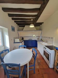 une cuisine avec une table blanche et des chaises bleues dans l'établissement La Chapelle - Campagne - 8pers - Rêve au Mans, à Thorée-les-Pins