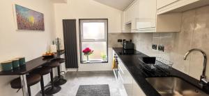une cuisine avec des comptoirs noirs et une fenêtre dans l'établissement Beautiful London home sleeps 6, 2 minutes to metro, à Londres