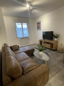 uma sala de estar com um sofá castanho e uma televisão em La Feuillette - Cosy - Wifi - 4 personnes - Rêve au Mans em Pontlieue