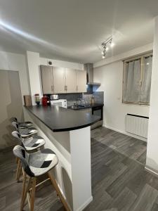 uma cozinha com um balcão preto e alguns bancos em La Feuillette - Cosy - Wifi - 4 personnes - Rêve au Mans em Pontlieue