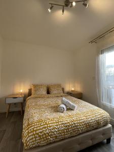 a bedroom with a bed with a yellow and white comforter at La Feuillette - Cosy - Wifi - 4 personnes - Rêve au Mans in Pontlieue