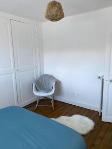 ein weißes Zimmer mit einem Stuhl und einem Teppich in der Unterkunft Le Contemporain - 5p - Centre Ecommoy - Rêve au Mans in Écommoy
