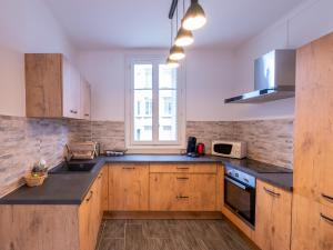eine Küche mit Holzschränken, einem Waschbecken und einem Fenster in der Unterkunft L'Escapade - Gare - Wifi - 6 personnes - Rêve au Mans in Le Mans