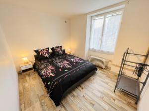 um quarto com uma cama com um edredão preto e uma janela em Le Lodge - Cosy - Wifi - 4 personnes - Rêve au Mans em Connerré
