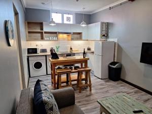 a small kitchen with a table and a refrigerator at Stoked Backpacker Apartments in Muizenberg