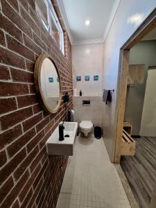 a bathroom with a sink and a brick wall at Stoked Backpacker Apartments in Muizenberg