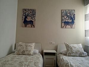 twee bedden in een kamer met twee schilderijen aan de muur bij ZUBICALM in La Zubia