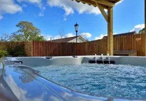 una bañera de hidromasaje en un patio trasero con una valla de madera en Finest Retreats - Little Dunley - Acorn Cottage en Bovey Tracey