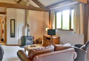 ein Wohnzimmer mit einem Ledersofa und einem TV in der Unterkunft Finest Retreats - Little Dunley - Acorn Cottage in Bovey Tracey