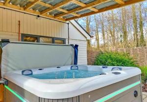 a jacuzzi tub sitting outside of a house at Finest Retreats - Little Dunley - Acorn Cottage in Bovey Tracey