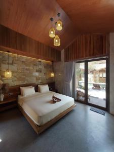 a bedroom with a large bed and a stone wall at Batatu Resort - Adults Only in Kuta Lombok