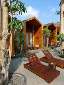 two wooden lounge chairs in front of a house at Batatu Villas in Kuta Lombok