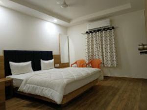 a bedroom with a bed with two chairs and a window at Hotel Kutchi Palace, Dwarka in Dwarka