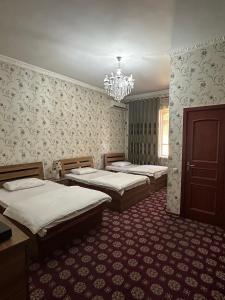 1 dormitorio con 3 camas y lámpara de araña en Hello Dushanbe Guest House en Dusambé
