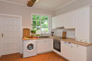 - une cuisine avec des placards blancs et un lave-linge dans l'établissement Altes Komödienhaus - Schloss Gelting, à Gelting