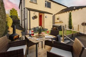 a patio with a table and chairs and a fireplace at Ellerthwaite Place X3 Bed House with Hot Tub in Central Windermere in Windermere