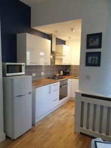 a kitchen with white cabinets and a microwave at Stylish ground floor 2 bedroomed apartment. in Barrow in Furness