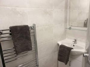 a white bathroom with a sink and a mirror at Stylish ground floor 2 bedroomed apartment. in Barrow in Furness
