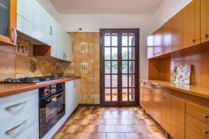 eine große Küche mit Holzschränken und einem Fenster in der Unterkunft La Casa delle Rose in Solanas