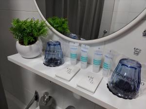 uma prateleira de casa de banho com garrafas de vidro azul e um espelho em M&M Apartment em Velika Gorica