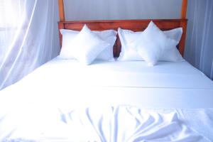 een bed met witte lakens en kussens erop bij The White Villa in Hikkaduwa