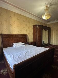 a bedroom with a large bed with a wooden headboard at Hello Dushanbe Guest House in Dushanbe