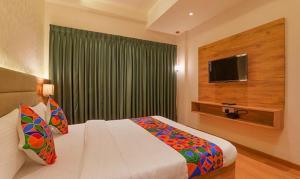 een slaapkamer met een groot bed en een televisie bij FabHotel Pratham Inn in Chinhat