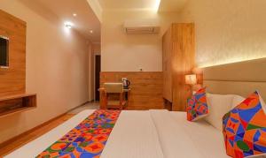een slaapkamer met een bed en een stoel erin bij FabHotel Pratham Inn in Chinhat