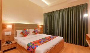 een slaapkamer met een groot bed voor een raam bij FabHotel Pratham Inn in Chinhat