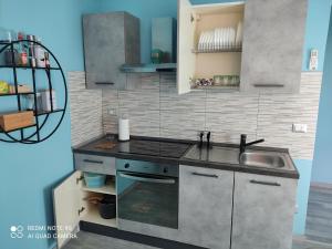 uma cozinha com um lavatório e um fogão forno superior em Il cortiletto em Vado Ligure