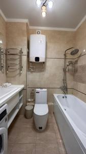 La salle de bains est pourvue de toilettes et d'une baignoire. dans l'établissement Luxe Appartments on Stepnoy, à Karaganda