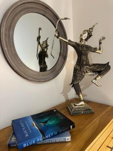a book and a statue on a table with a mirror at 1A Priscilla Close in Earlham