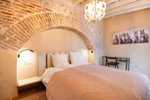 a bedroom with a large bed with a brick wall at Historic Loft in Kangen House Jerez in Jerez de la Frontera