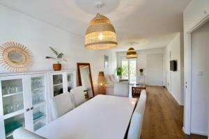 een eetkamer met een witte tafel en stoelen bij Charmante maison avec piscine in Puilboreau