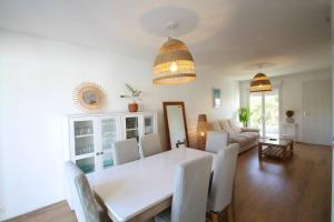 comedor y sala de estar con mesa blanca y sillas en Charmante maison avec piscine en Puilboreau