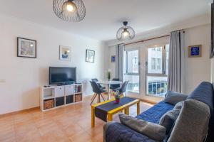 a living room with a blue couch and a tv at Flatguest Sardina Home pool in Gáldar