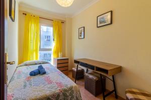a bedroom with a bed and a desk and a window at Flatguest Sardina Home pool in Gáldar +8 photos