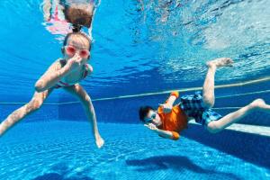 - deux jeunes enfants nageant dans une piscine dans l'établissement Lovely 6 Berth Caravan At Cherry Tree Holiday Park, Ref 70403c, à Great Yarmouth