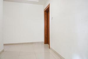 an empty room with white walls and a wooden door at FabExpress Sathvik Executive in Pune