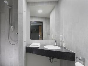 a bathroom with a sink and a mirror at B&B Hotel Berlin-Airport in Schönefeld